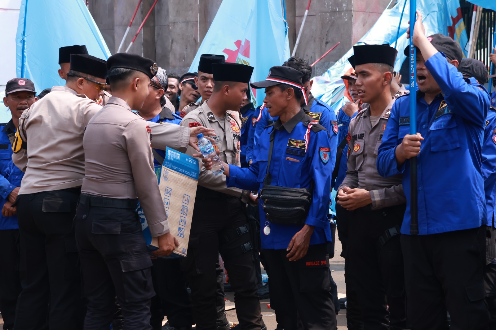 Polisi Bagikan Air Mineral dan Roti di Tengah Aksi Buruh di Depan Gedung DPR/MPR RI.